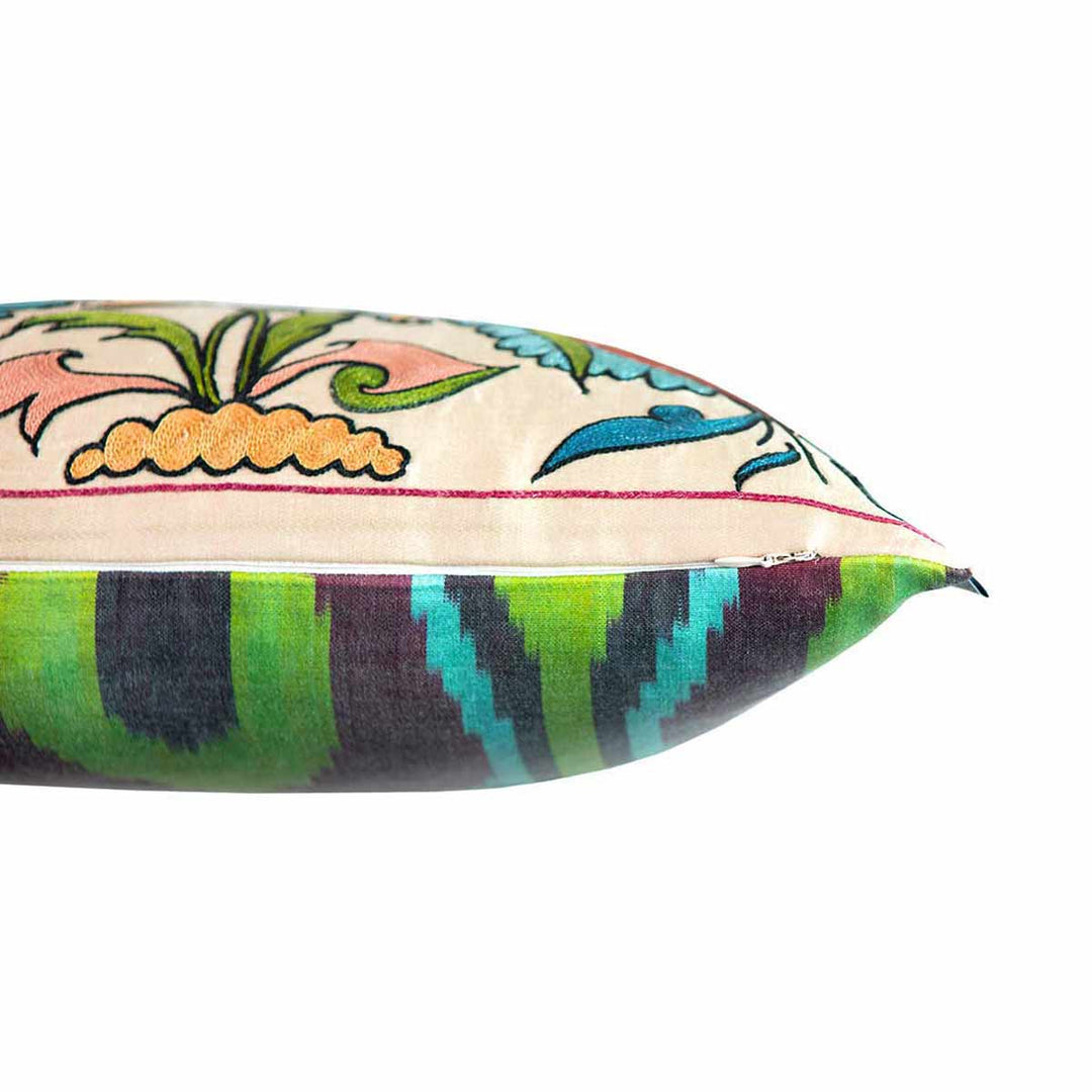 Side view of Mekhann's cream tulips and pomegranates embroidered cushion,  here we can see where the cream front face of the cushion meets the green and blue toned ikat lining on the back of the cushion.