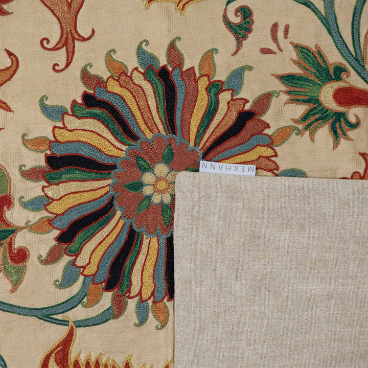 Alternative folded view of Mekhann's cream iznik petite throw, showing the cream back lining with the Mekhann label.