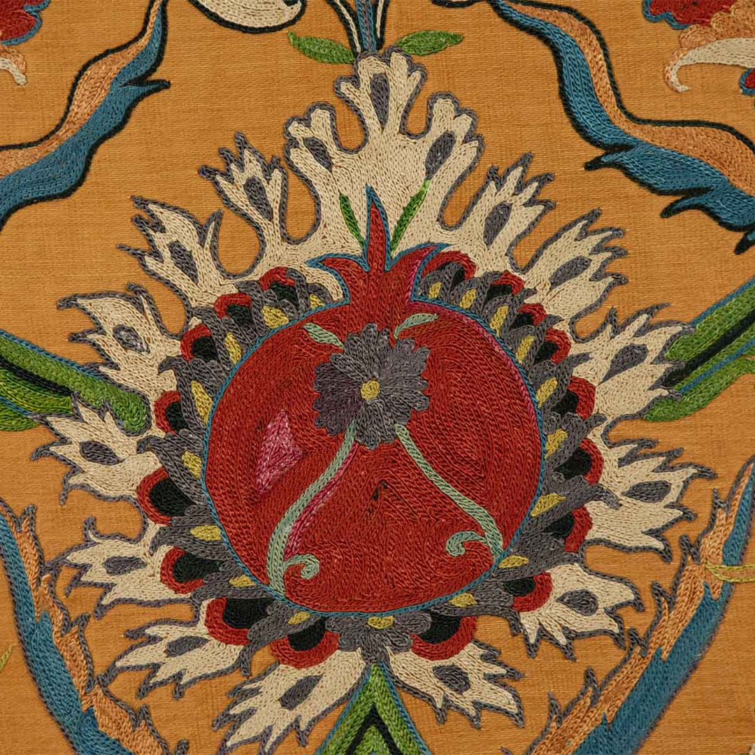 Close up view of Mekhann's tulip caramel petite throw, reveals the intricate stitching and texture of the lush tulip embroidery using cream, red, blue, light yellow and grey silk yarns.