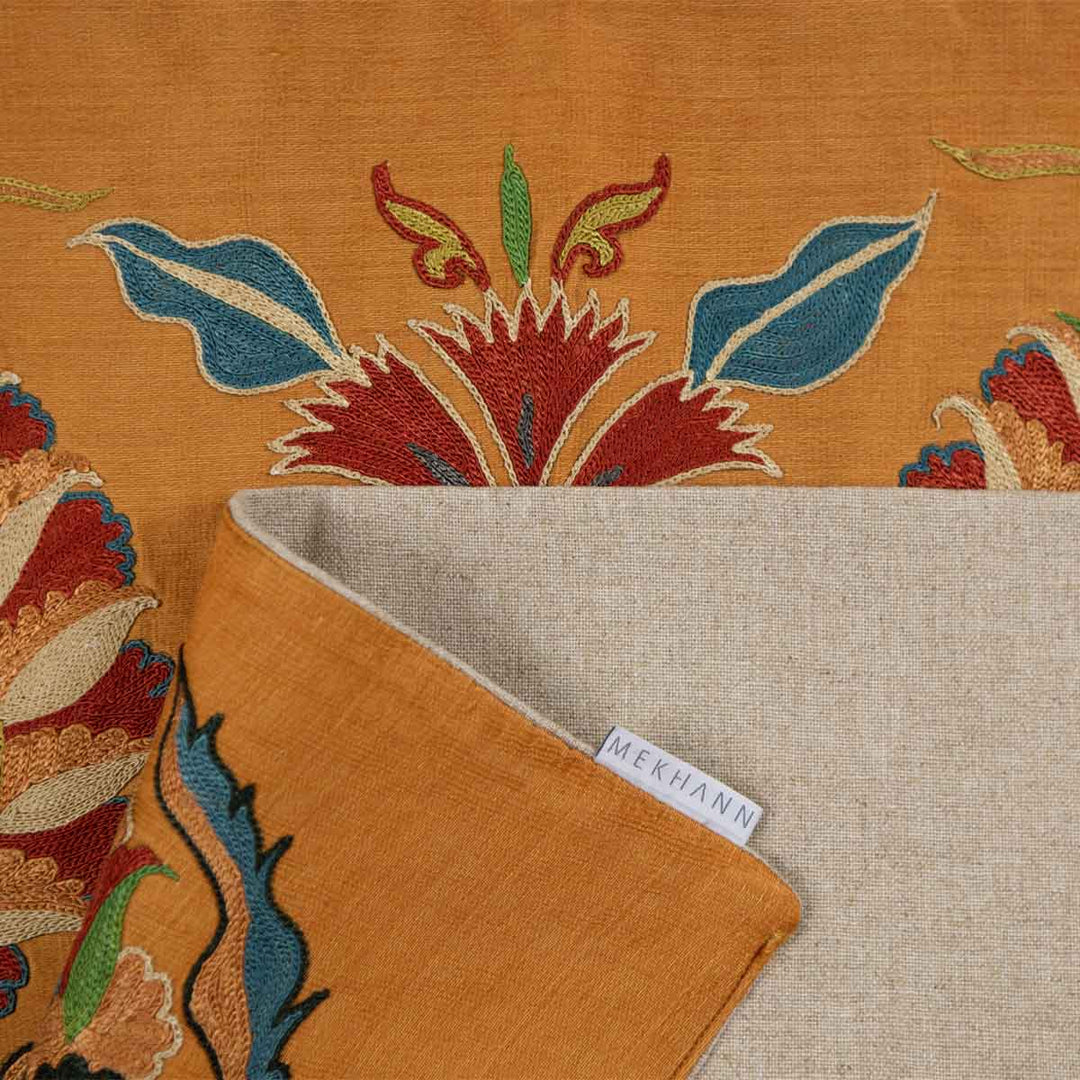 Folded view of Mekhann's tulip caramel petite throw, showing the back lining fabric to the throw with the Mekhann label in the image.