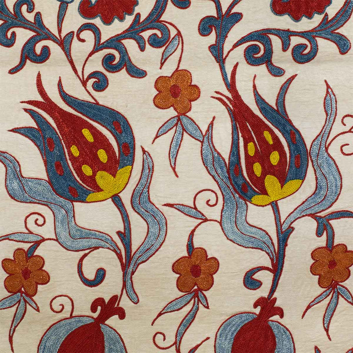 Detail view of Mekhann's cream tulips runner, showing up close the hand embroidered tulip design in blue, red, yellow and navy, all set against a delicate cream coloured silk base.