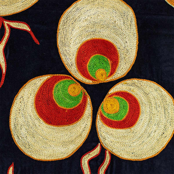 Close up view of Mekhann's navy, velvet cintamani throw. Bringing you close to the hand embroidered cintamani pattern where you can see all the attention to detail of the throws hand embroidery, all set on a background of navy velvet.