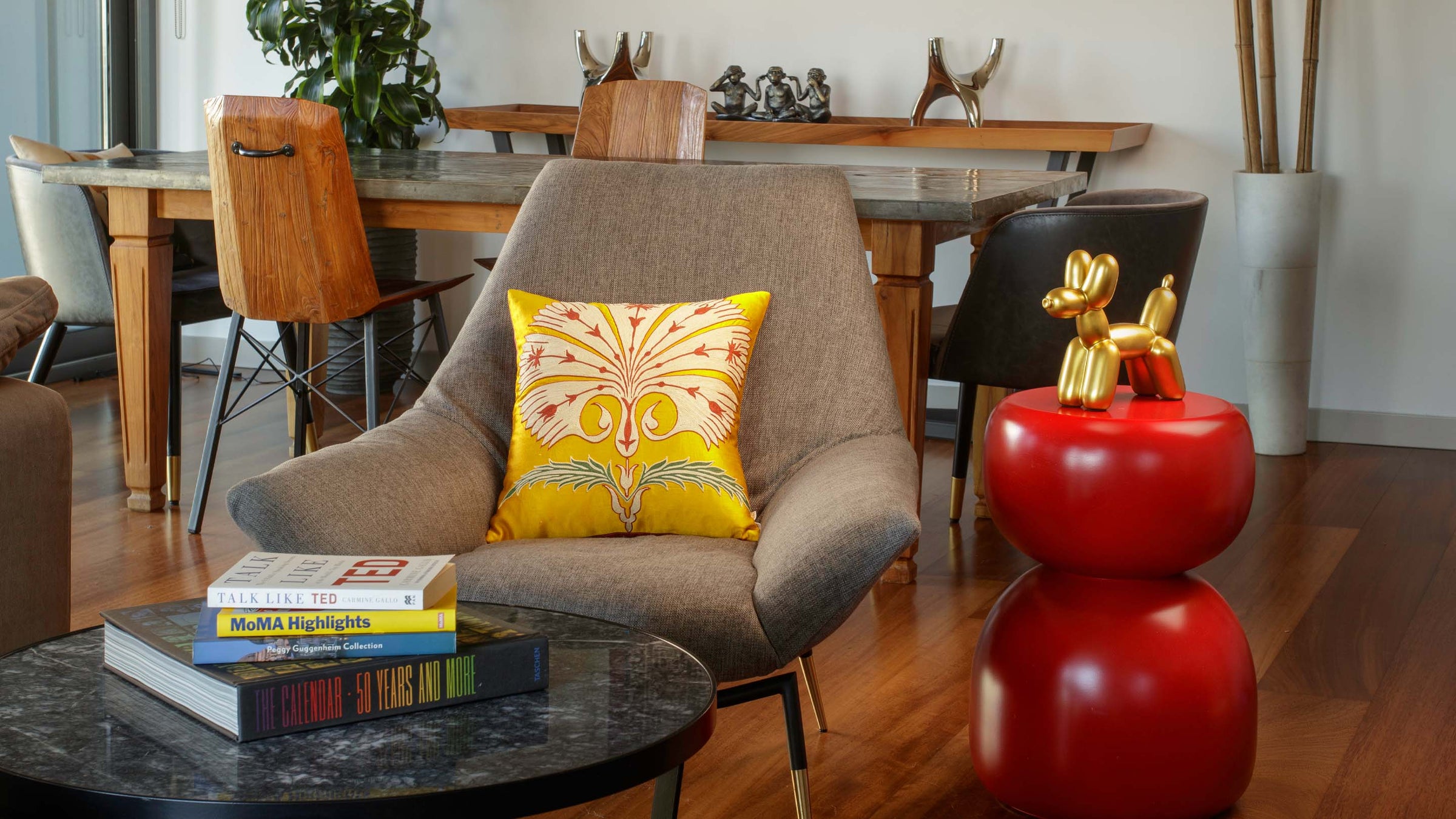 Yellow designer cushion handcrafted from embroidered silk by Mekhann, styled on a modern armchair in contemporary interior