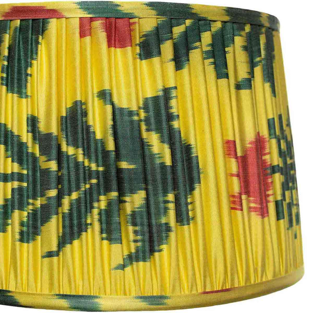 Close-up of Mekhann's saffron yellow silk lampshade with floral ikat patterns, emphasizing the precision of hand-pleating and dye quality.