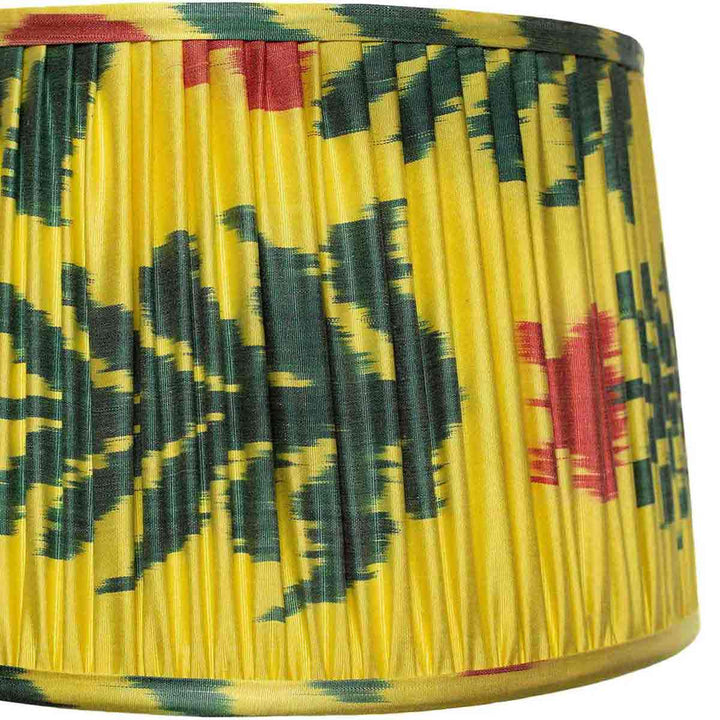 Close-up of Mekhann's saffron yellow silk lampshade with floral ikat patterns, emphasizing the precision of hand-pleating and dye quality.