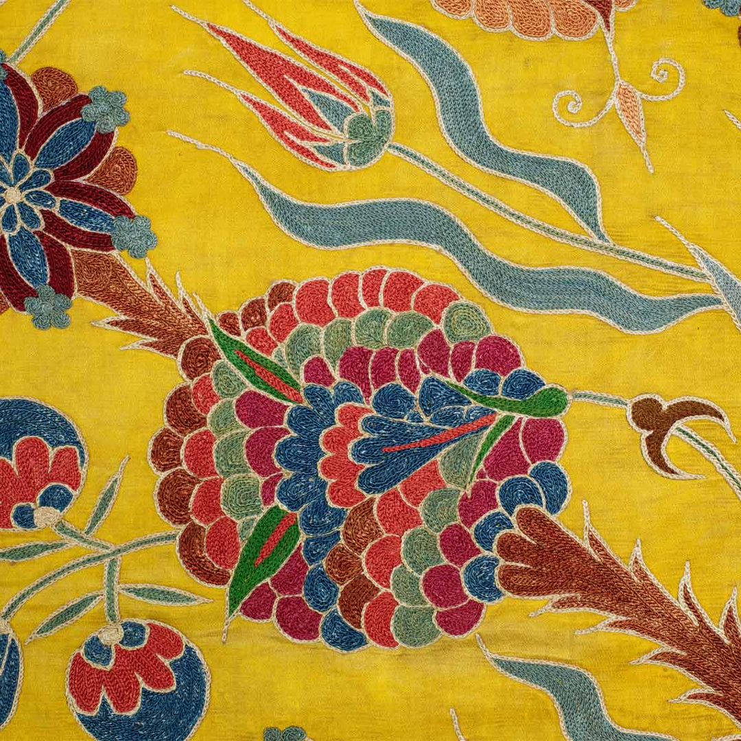 Close up view of Mekhann's yellow iznik throw, showcasing how the colours complement each other. With the main centre motif in brown, green, pink and blue tones.