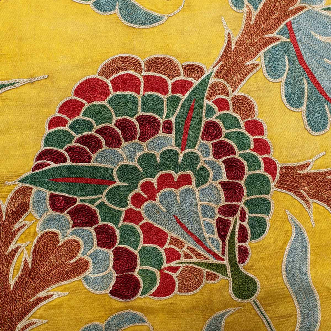 Close up view of Mekhann's yellow iznik throw, where you can see the unique dying method of the silk yarns shine through on this final product, showing different brown hues on the brown thread.