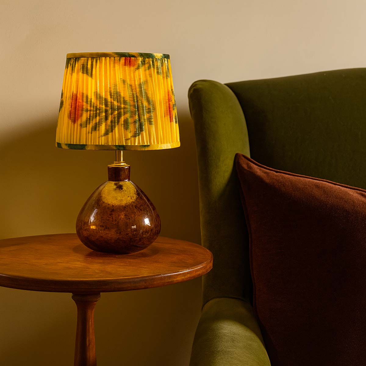 Collection of Mekhann's hand-pleated silk ikat lampshades in various vibrant colours and floral patterns displayed on wooden shelves.