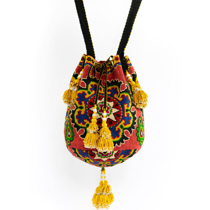 Full view of Mekhann's arabesque clementine bucket bag, showcasing the unique textile patterns and handcrafted tassel embellishments.