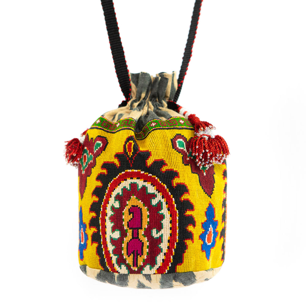 Full front view of Mekhann's yellow arabesque embroidered bucket bag, showing the bag in full including the black strap. 