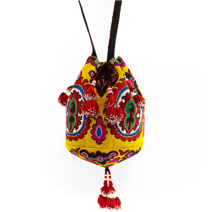 Full view of Mekhann's yellow arabesque bucket bag, showcasing the unique textile patterns and handcrafted tassel embellishments.