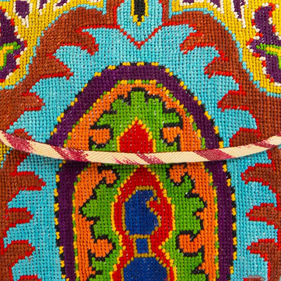 close up view of Mekhann's blue and multicoloured arabesque embroidered cross-body bag, showing the detail of the colourful cross stitching detail.