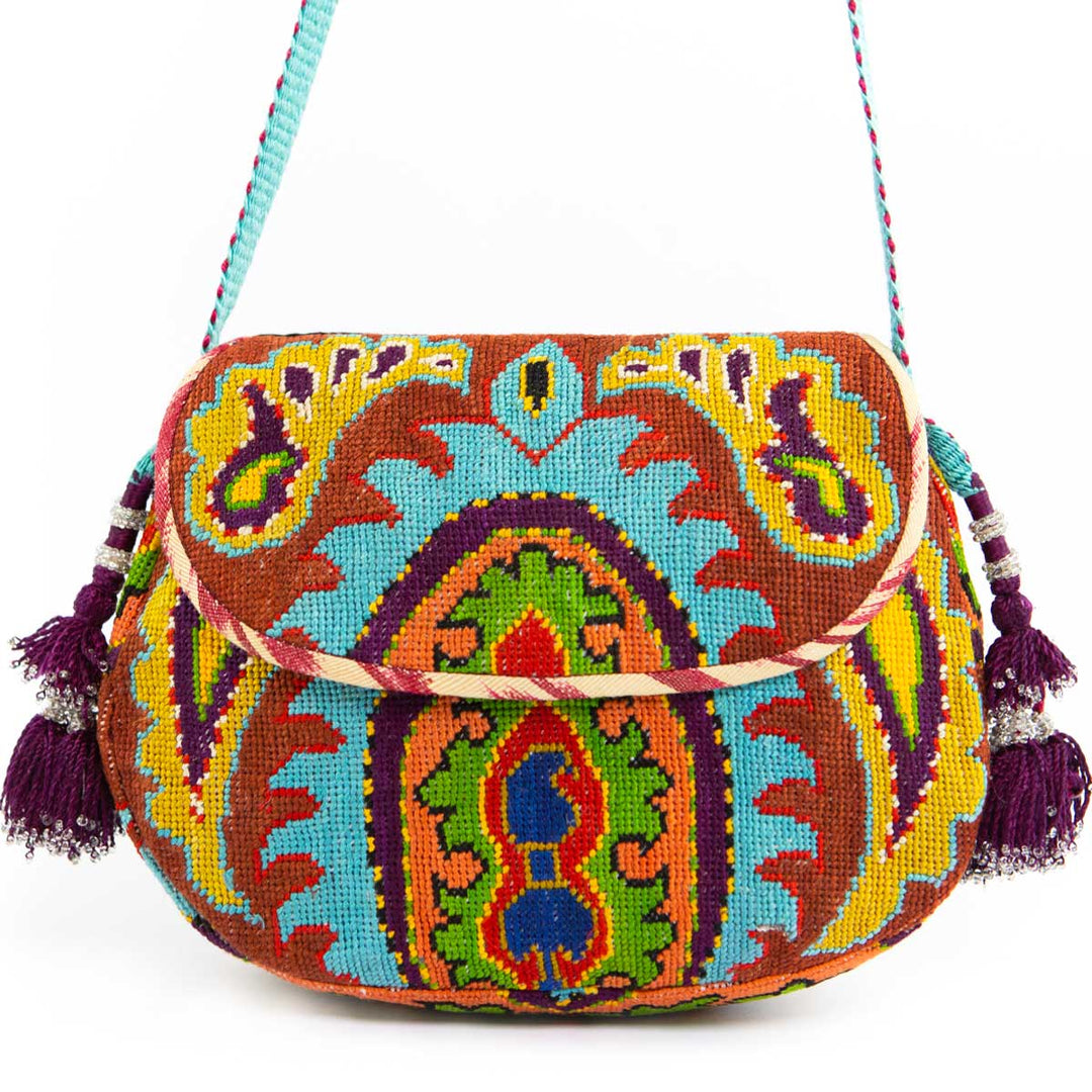 Front view of Mekhann's blue and multicoloured arabesque embroidered cross-body bag, showing off its bold colours and purple tassels.