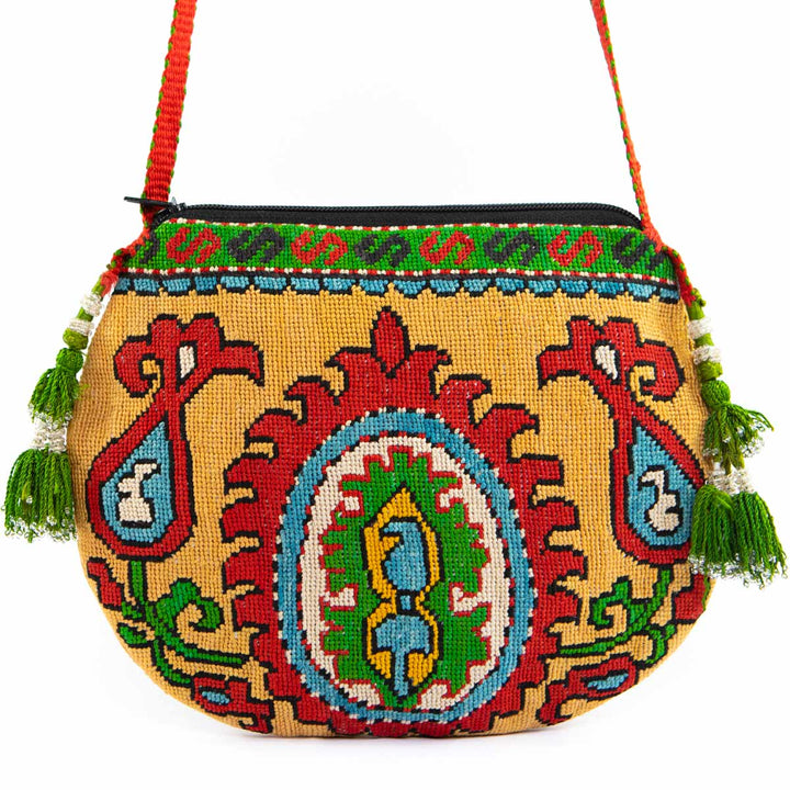 Front view of Mekhann's multicoloured arabesque embroidered cross-body, with a bold red strap and bight green tassels.