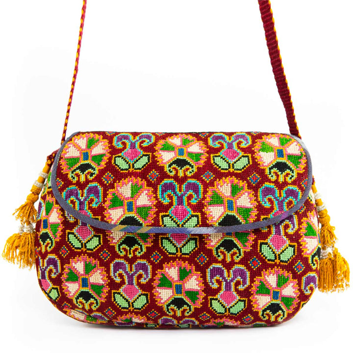 Front view of Mekhann's arabesque embroidered cross-body bag, with a detailed pattern and golden tassels.