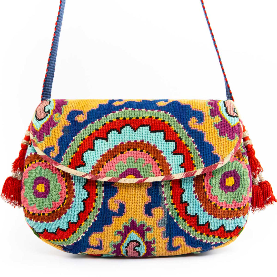 Front view of Mekhann's arabesque embroidered cross-body bag, with a bold central motif and red tassel accents.