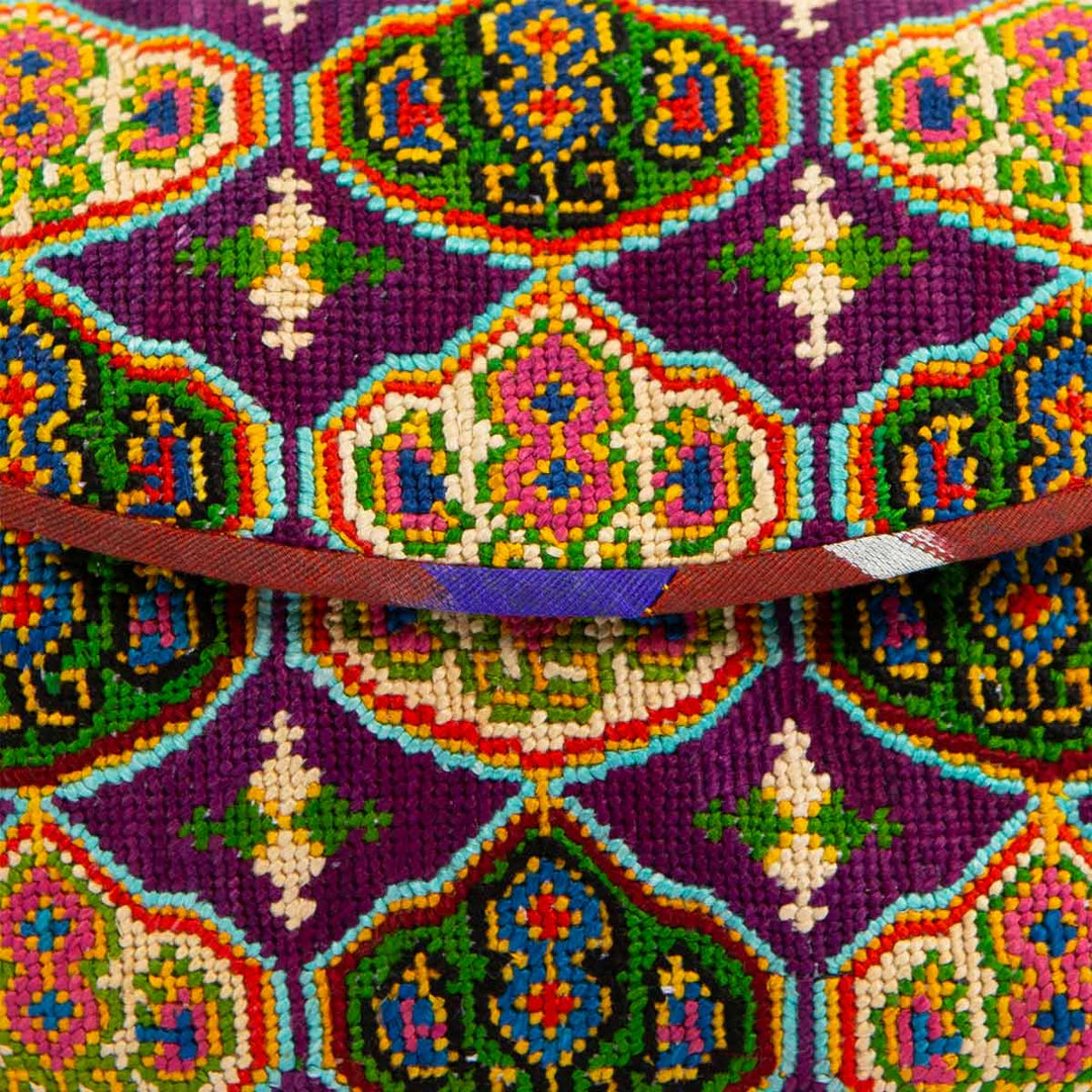 Close up view of Mekhann's royal purple arabesque embroidered cross-body bag, displaying all the design details and stitching on the bags surface.