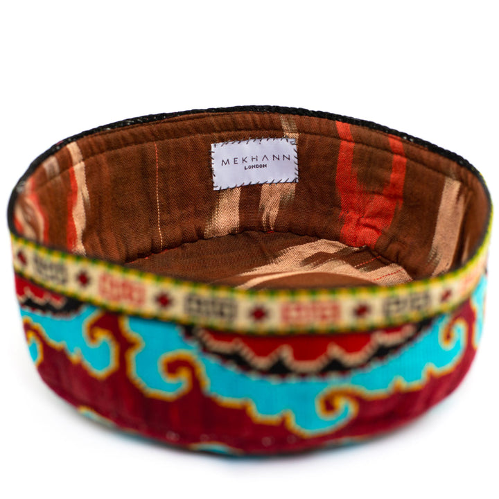 Full frame view of Mekhann's multicoloured arabesque skull cap, showing how the colours of the embroidered exterior matches the earth toned ikat lining. 