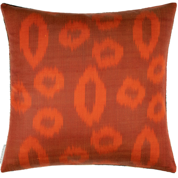 Back view of Mekhann's black and orange velvet cushion, showing the circle ikat pattern on the back of the cushion in shades of orange.