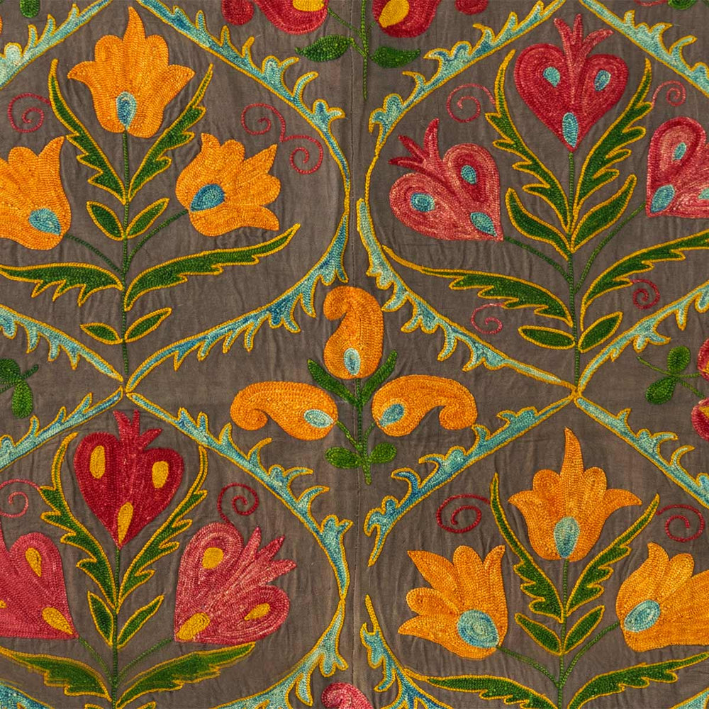 Detailed view of Mekhann's black nurata throw, revealing the intricate detailing of the hand embroidered patterns, with the main colours being red, yellow, green and blue.