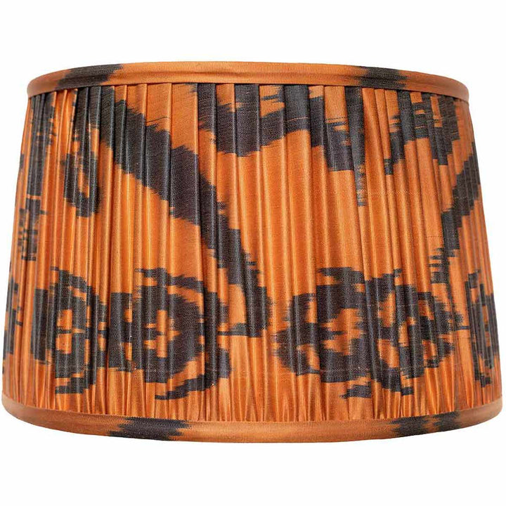 Front view of Mekhann's black and orange ikat silk lampshade, hand-pleated with bold patterns using sustainable dyes.