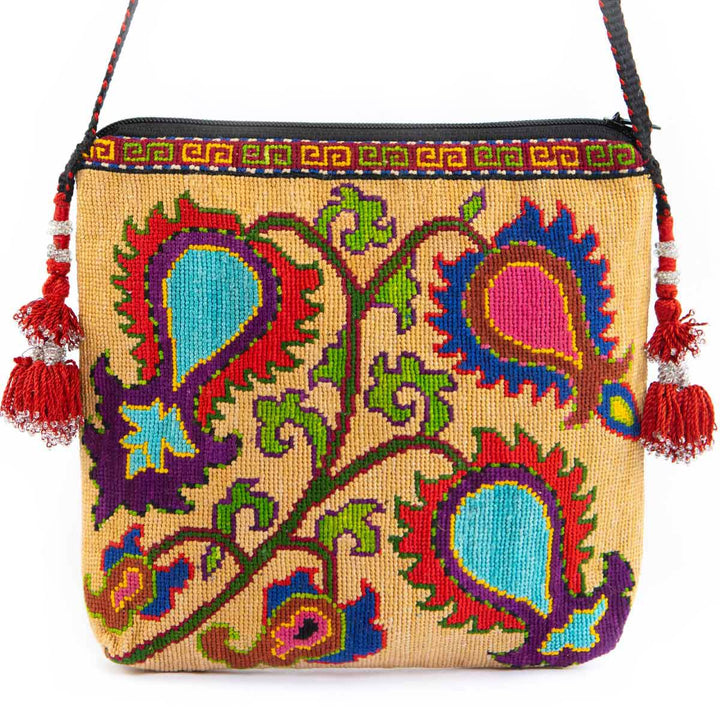 Front view of Mekhann's beige botanical embroidered cross-body bag, adorned with vibrant hand-embroidery and playful red tassels.