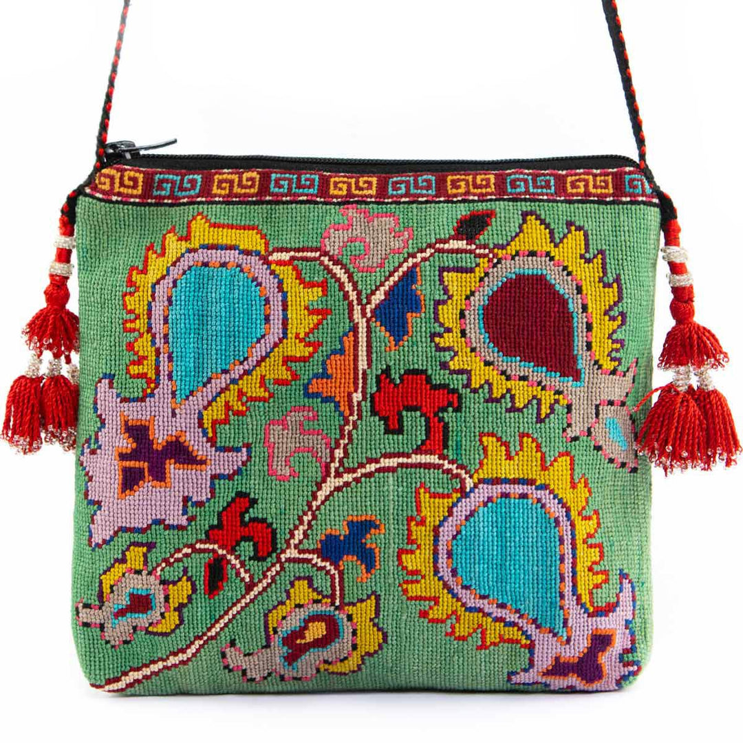 Front view of Mekhann's mint botanical embroidered cross-body bag, showing it's red tassels and black strap.