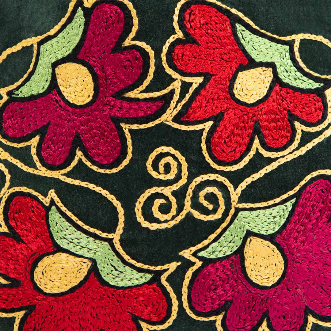Close up view of Mekhann's botanical dark green velvet pouch, showing off the attention to detail put into every stitch on the embroidered flowers.