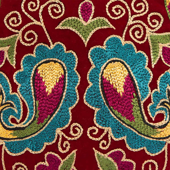 Close up view of Mekhann's botanical dark maroon velvet pouch, showing off the attention to detail in the cross stitch method on it's surface.