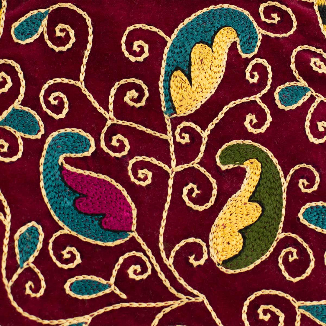Close up view of Mekhann's botanical deep maroon velvet pouch, showing off the botanical details of the embroidered surface, showing the attention to detail.