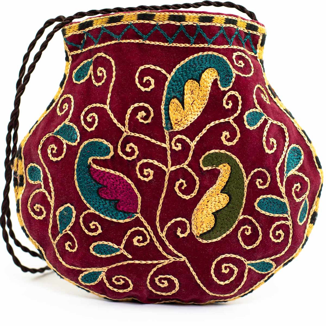 Alternative view of Mekhann's botanical deep maroon velvet pouch, showing a filled version of the bag to better display the bags ability to hold essentials. 