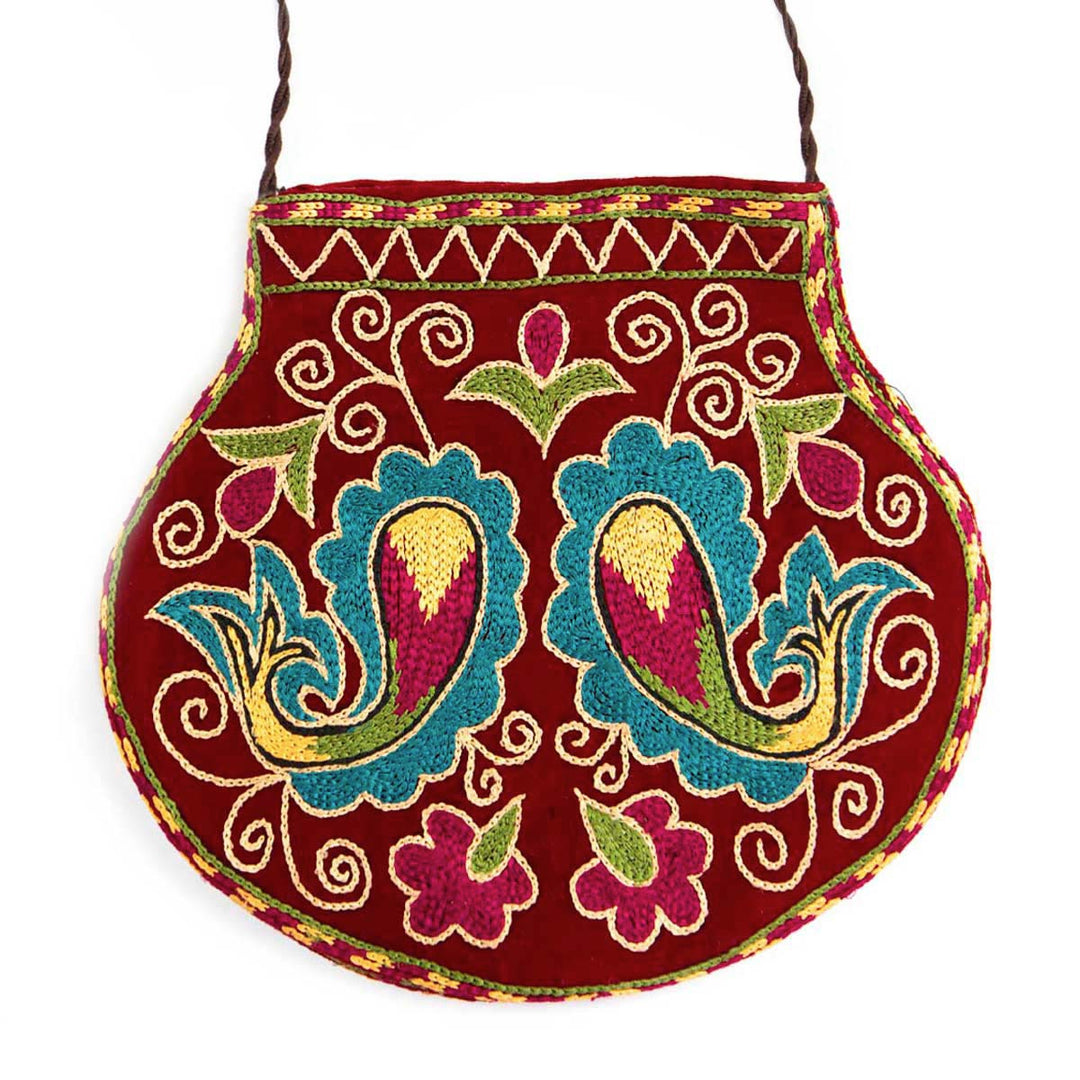 Front view of Mekhann's botanical dark maroon velvet pouch, displays a pink, blue, green and yellow embroidered collection of patterns.