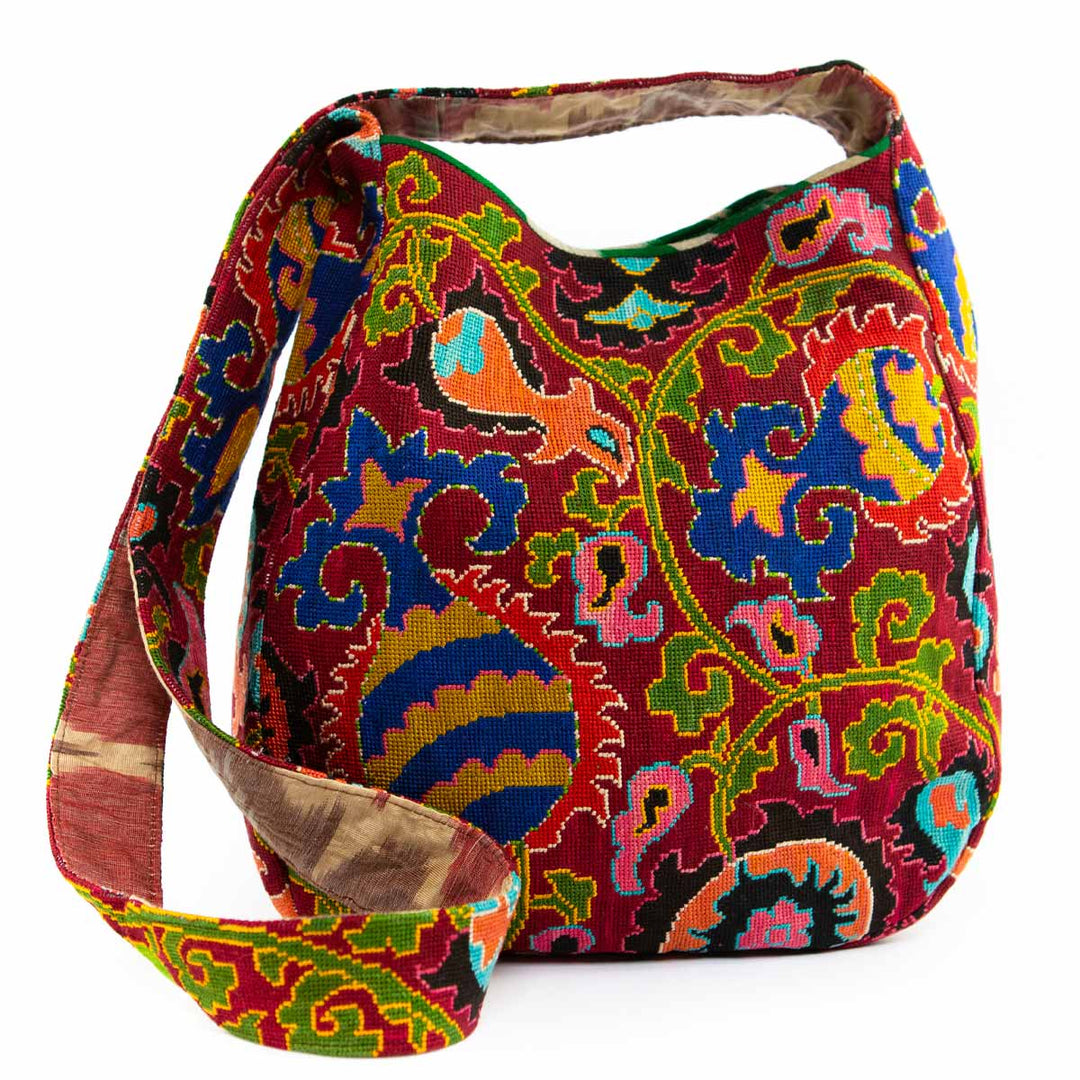 Front view of Mekhann's multicoloured embroidered large shoulder bag shown with the strap down, with a kaleidoscopic pattern and rich colour palette.