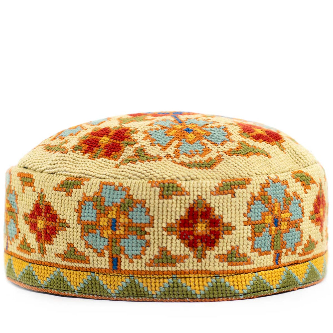 Front view of Mekhann's botanical cream skull cap, displaying a bright range of embroidered botanical patterns on a cream base.