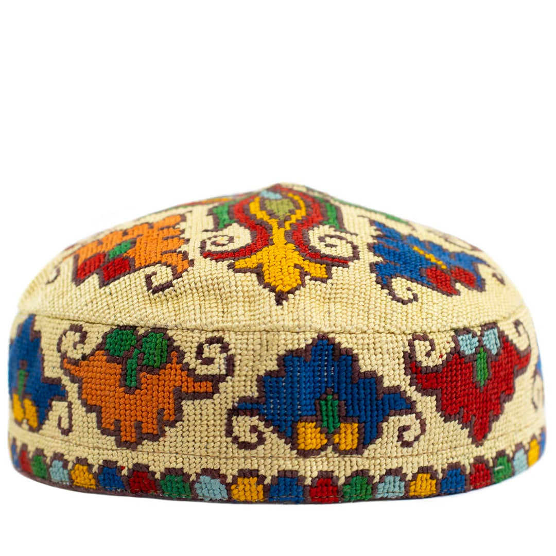 Front view of Mekhann's botanical cream skull cap, with a colourful display of hand embroidered patterns in blue, orange, red and yellow.