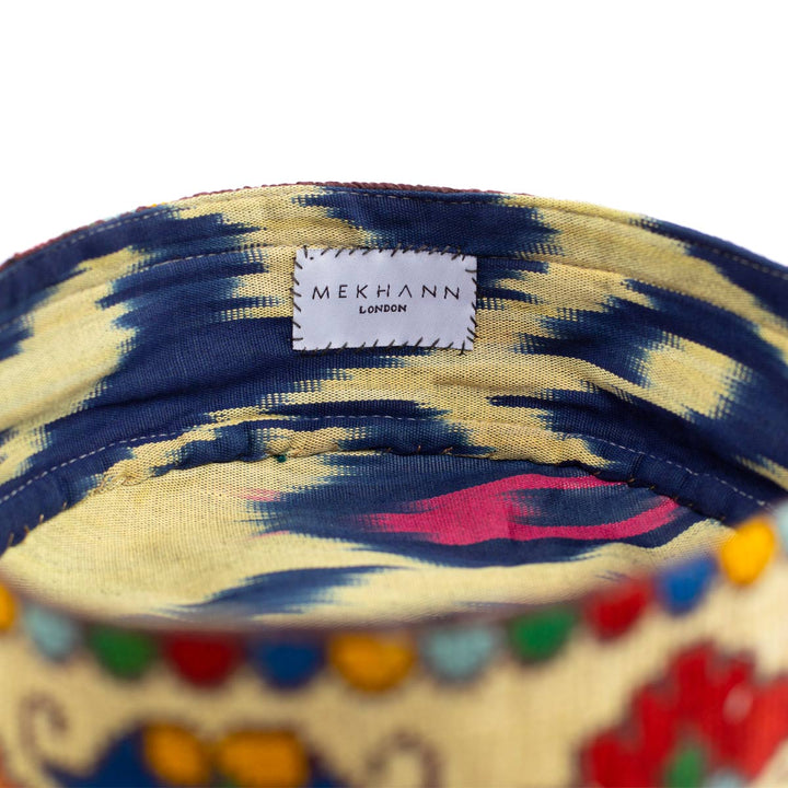 Inside view of Mekhann's botanical cream skull cap, exposing the ikat skull cap lining in blue, cream and pink to complement the external colours.