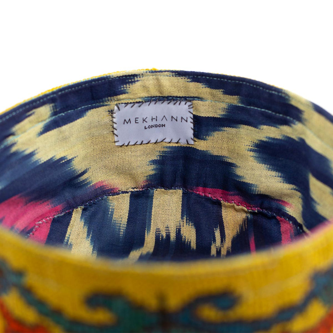 Inside view of Mekhann's botanical yellow skull cap, the blue, cream, and pink ikat lining can be seen, the ikat has been used for comfort and durability. 
