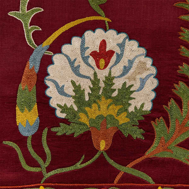 Close up view of Mekhann's maroon botanical petite throw, displaying the precision of the botanical motifs against a vibrant maroon background.