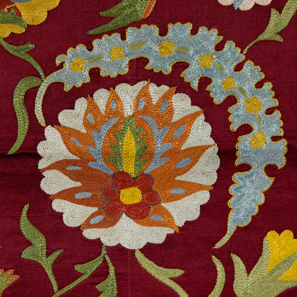 Detailed view of Mekhann's maroon botanical petite throw, with elaborate botanical embroidered patterns on the maroon silk background.