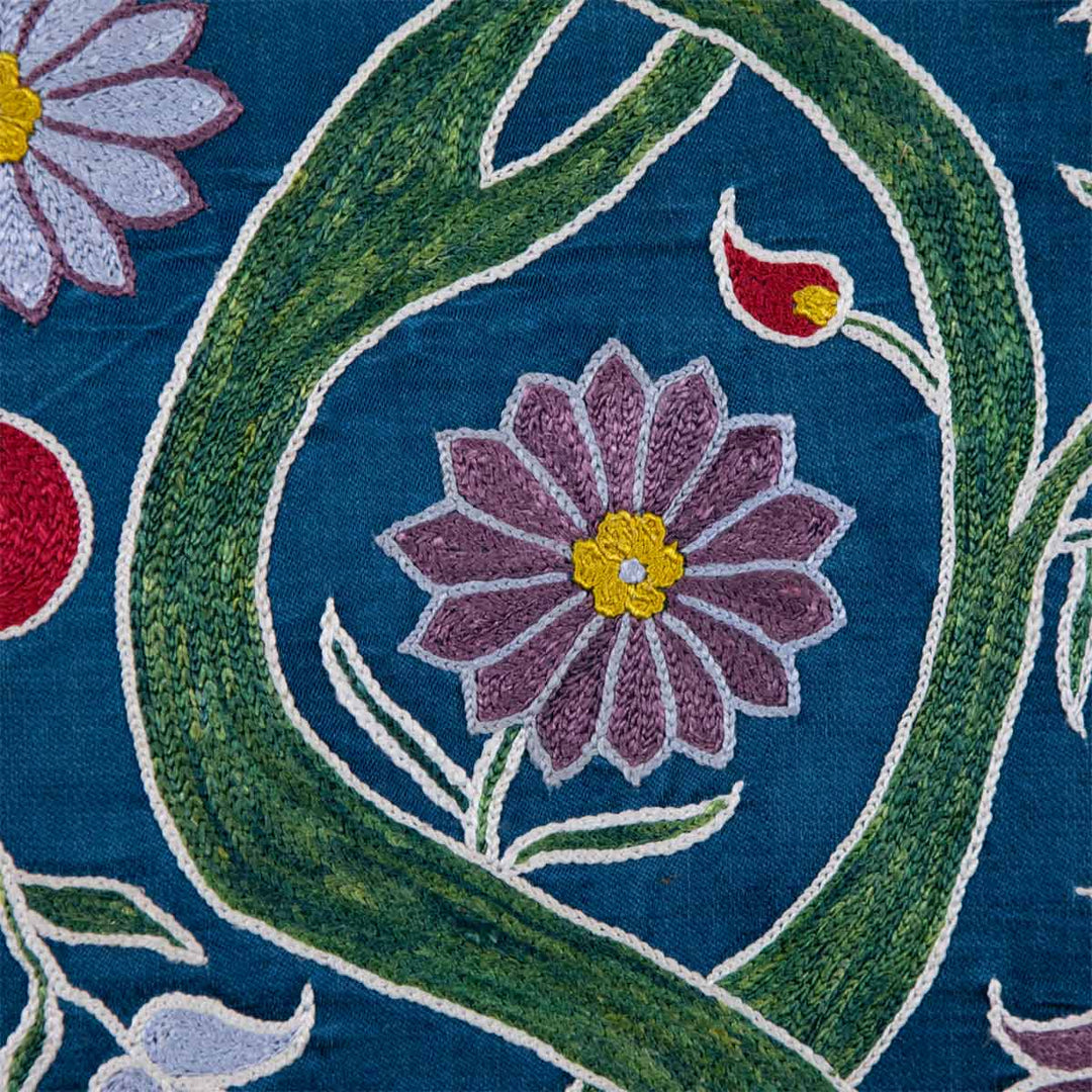 Detailed view of Mekhann's navy botanical runner runner, showing the embroidered branches of tree design, revealing a flower detail growing from it, all set against a navy silk background.