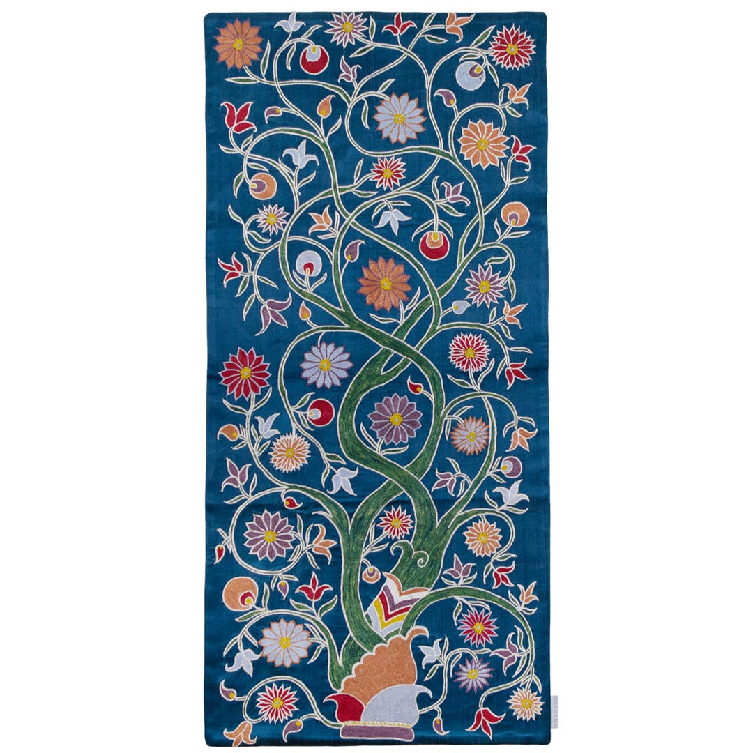 Front view of Mekhann's navy botanical tree runner, displaying a tree full of botanical patterns, with flowers and leaves in warm and cool tones, stretching across the entire length. All these details have been hand embroidered onto the silk navy background .