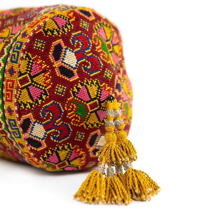 Bottom view of Mekhann's multicoloured embroidered carnations bucket bag, Showing off the yellow golf tassel is has. 