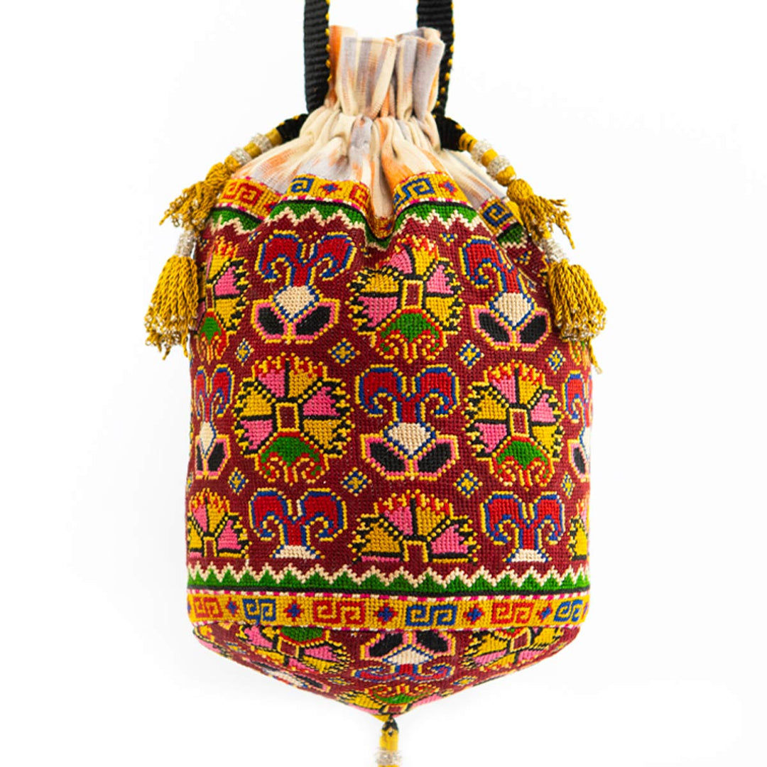 Front view of Mekhann's multicoloured embroidered carnations bucket bag with a vast collection of patterns and red tassel details.