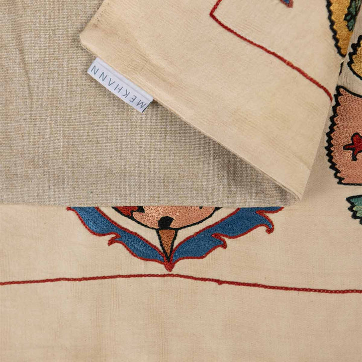 Folded view of Mekhann's carnations petite throw, showing the back lining of the throw alongside the Mekhann label.