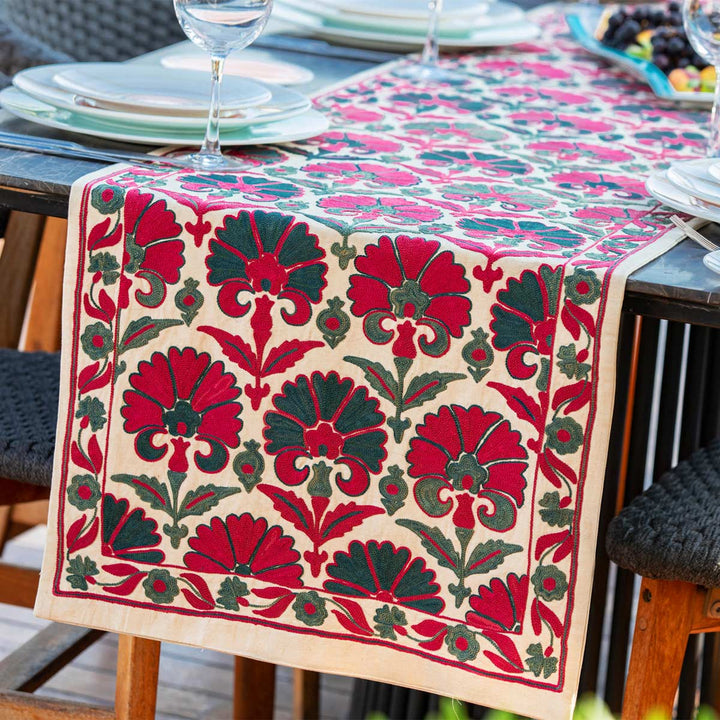 In use view of Mekhann's carnations runner in pink and teal, showing the end of the runner being used as part of a table display. Allowing someone to view the ways the silk runner can be used.
