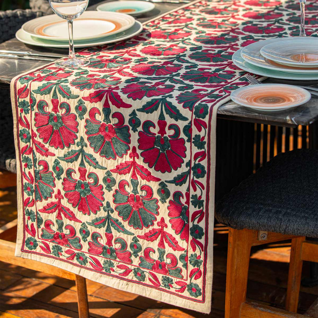 In use view of Mekhann's carnations runner in pink and teal, showing an angle of the embroidered carnations silk runner being used as part of table display, suggesting ways someone could use the product.