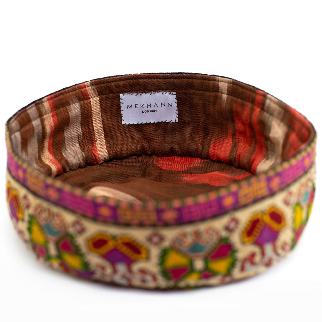 Full frame view of Mekhann's multicoloured carnations skull cap, showing how the colours of the ikat lining complements the colourful embroidered exterior of the skull cap. 