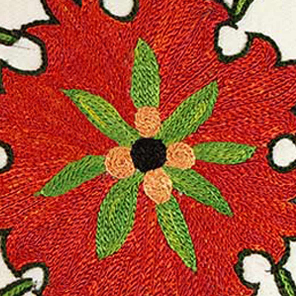 Close up view of Mekhann's multicoloured Pomegranates and Tulips embroidered cushion. Showing upclose the red, green and black embroidered centre of one of the flower motifs.