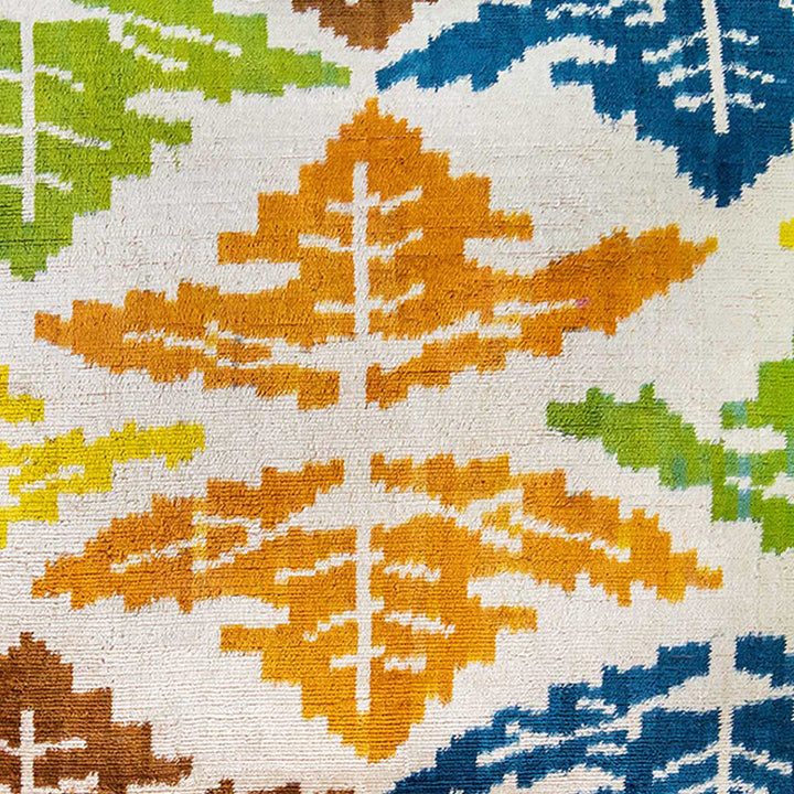 Close up view of Mekhann's leaves patterns velvet cushion, showing one of the velvet patterns up close in orange, green and navy blue.