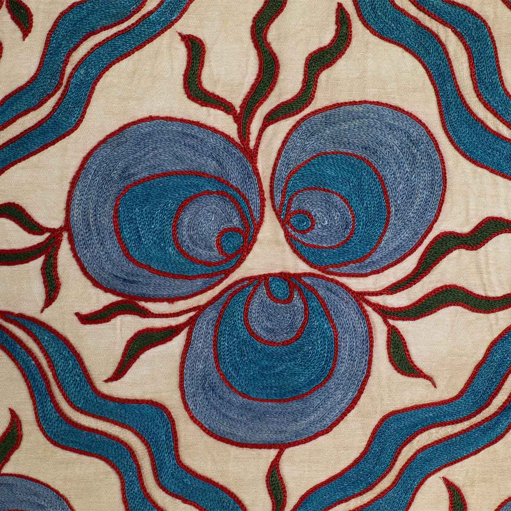 Close up view of Mekhann's cream cintamani runner, showing all of the hand embroidered details on the cintamani patterns in a bright blue with a red outline, making it stand out on the cream silk background.